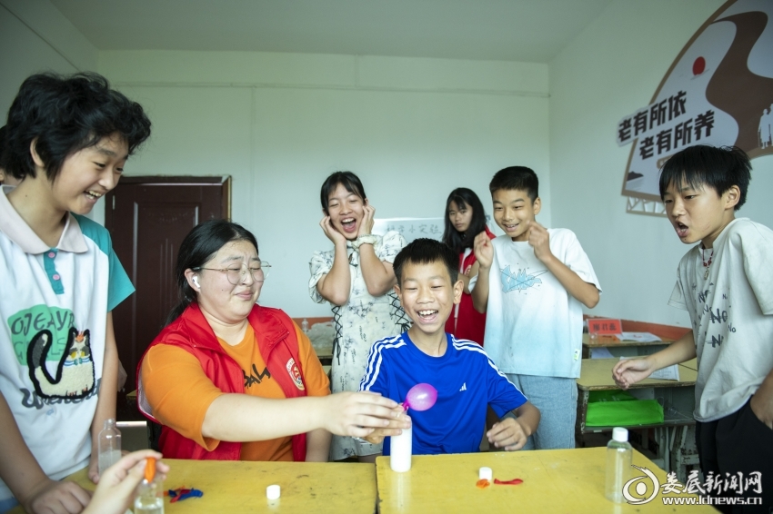 7月27日,大学生志愿者和孩子们体验科学小实验。