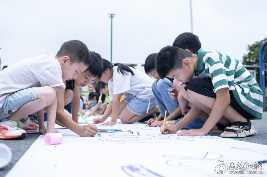 7月27日,孩子们在百米长卷上绘画。