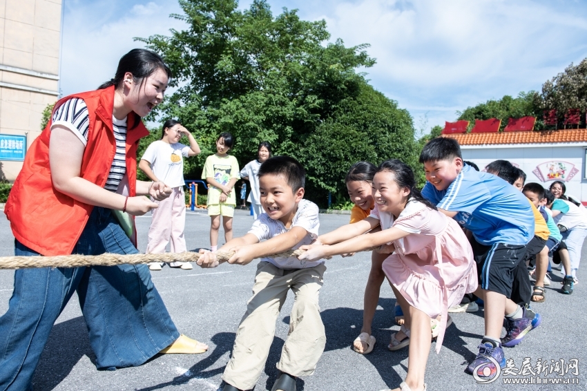 7月26日,大学生志愿者和孩子们一起拔河。
