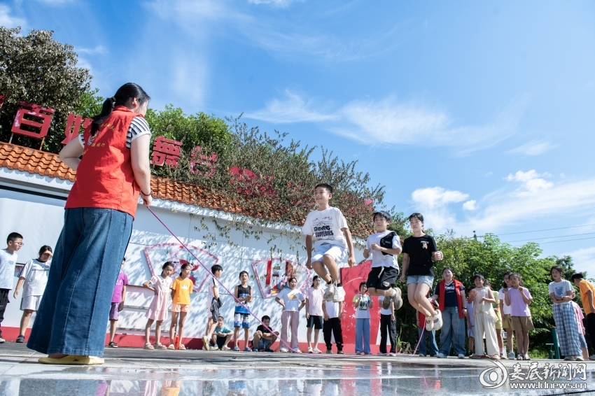 7月26日,大学生志愿者和孩子们一起跳绳。