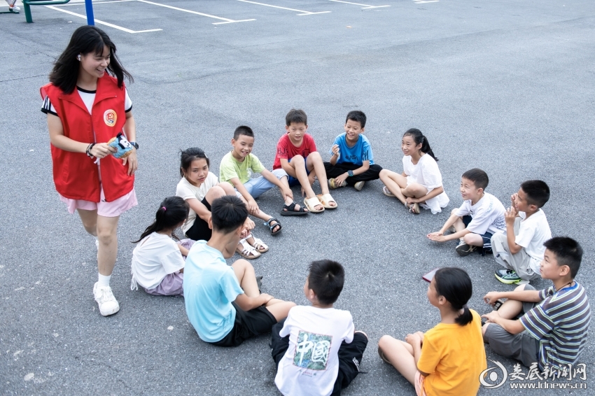 7月25日,大学生志愿者和孩子们一起玩丢手绢。——2